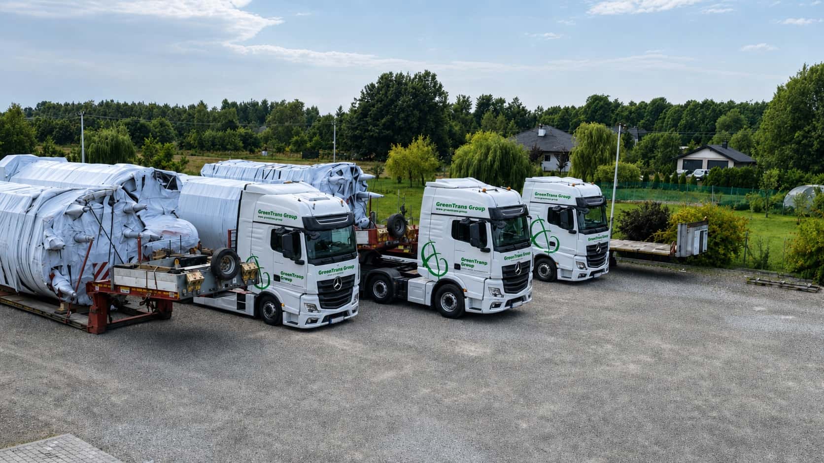 Three GreenTrans Group tractor units carrying oversized industrial equipment at a site